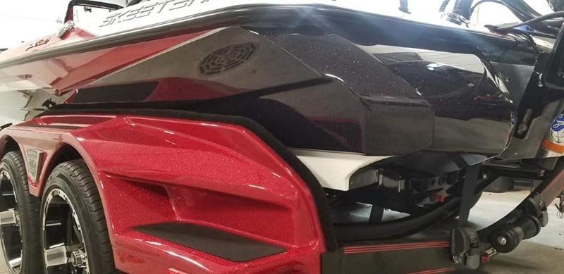 A red and black boat is parked in a garage.