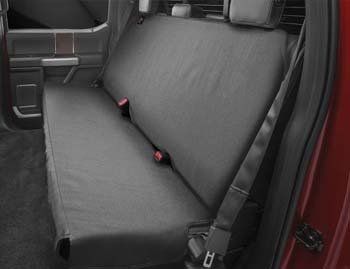 The back seat of a red truck with a black seat cover.