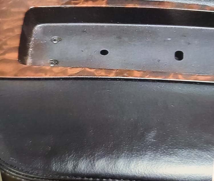 A close up of a black leather chair with a wooden trim.
