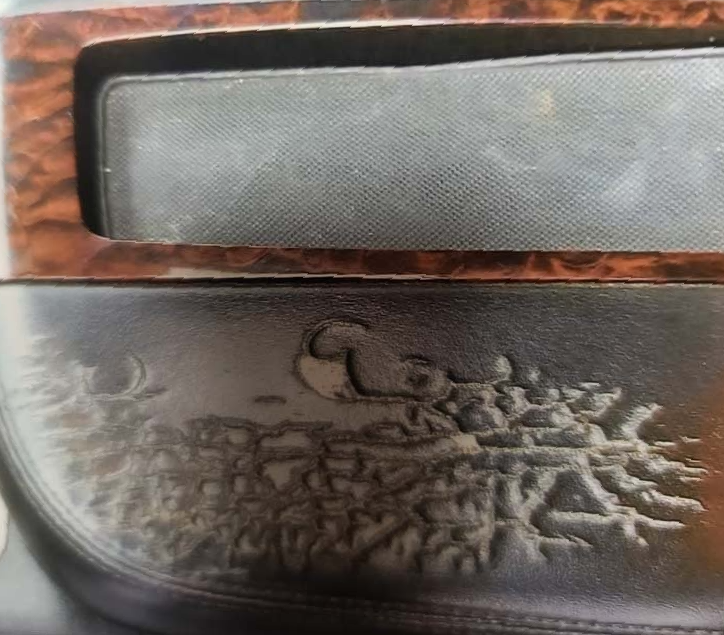 A close up of a car door with a wood trim
