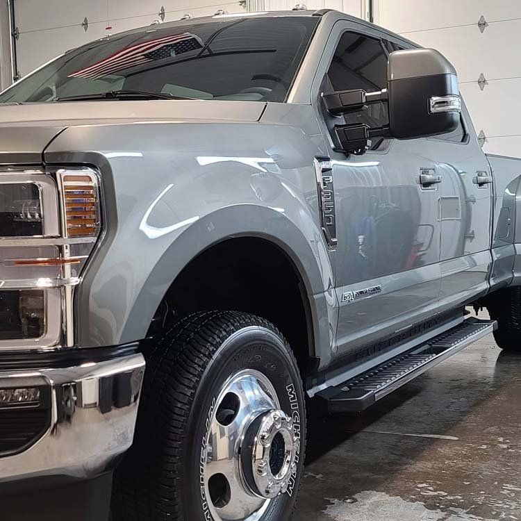 A gray truck is parked in front of a garage door.