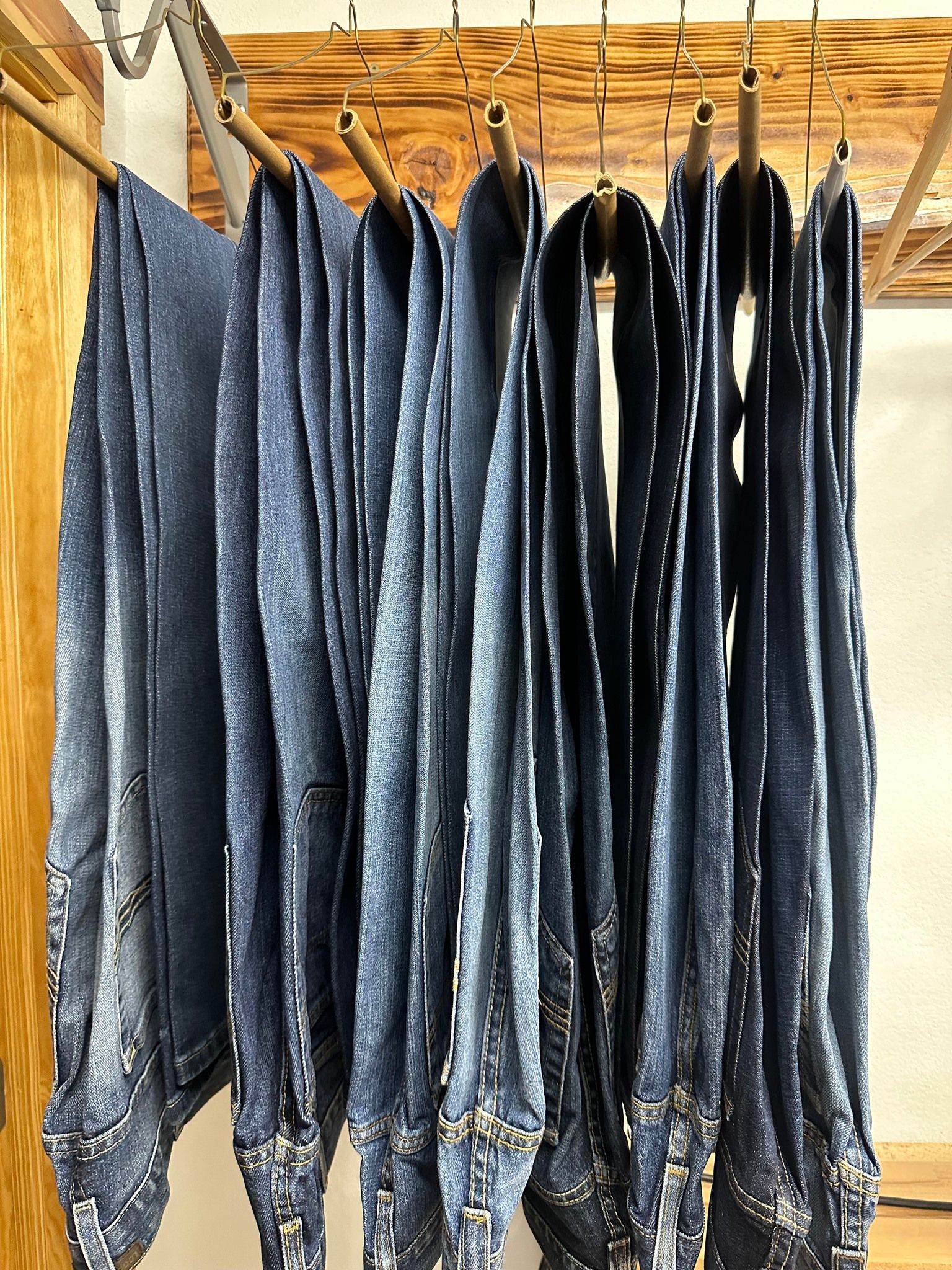 Dark blue jeans hanging on wooden racks to dry indoors