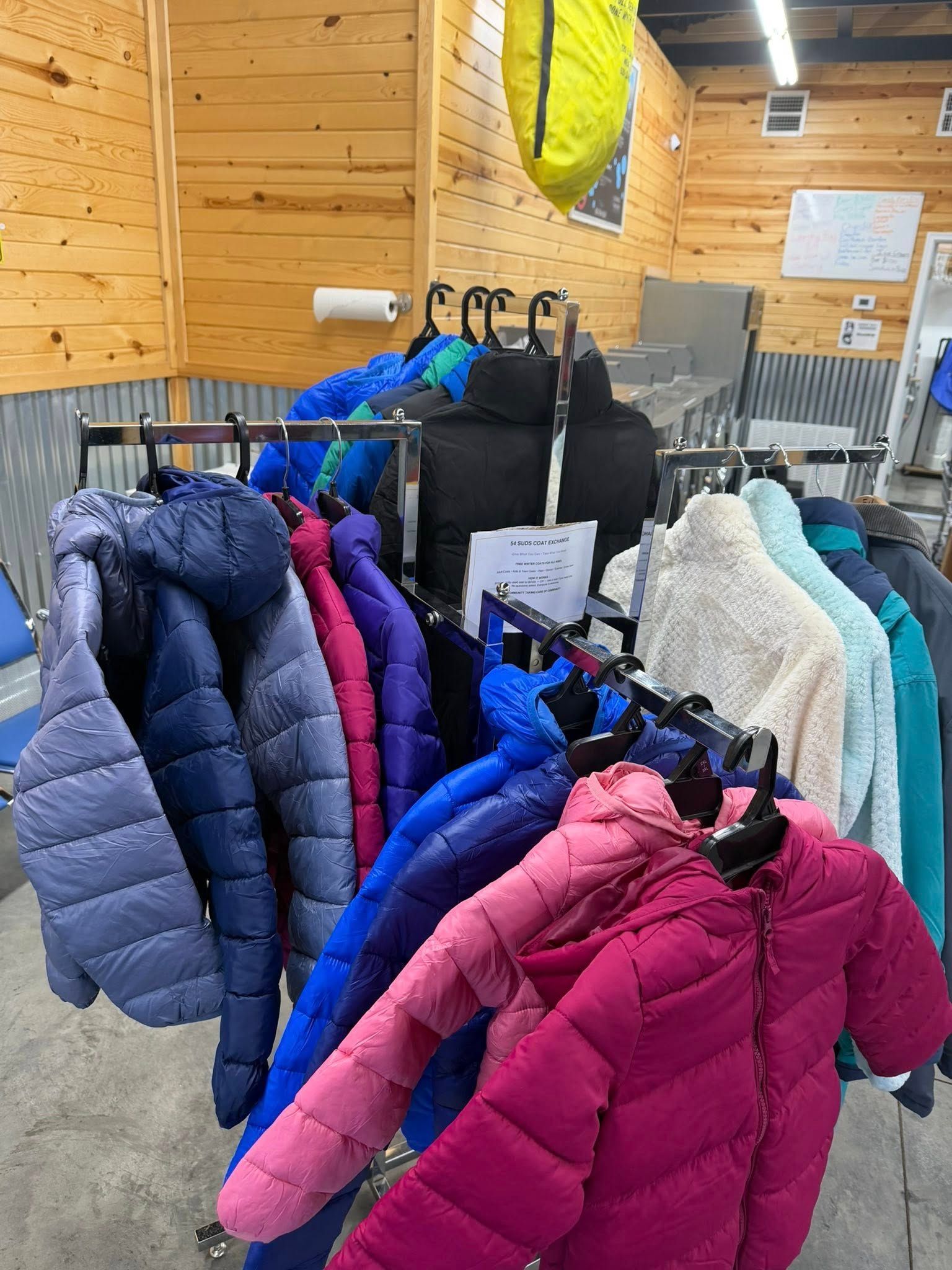 Bright winter coats on a rack inside a wood-paneled store or lodge gift shop.