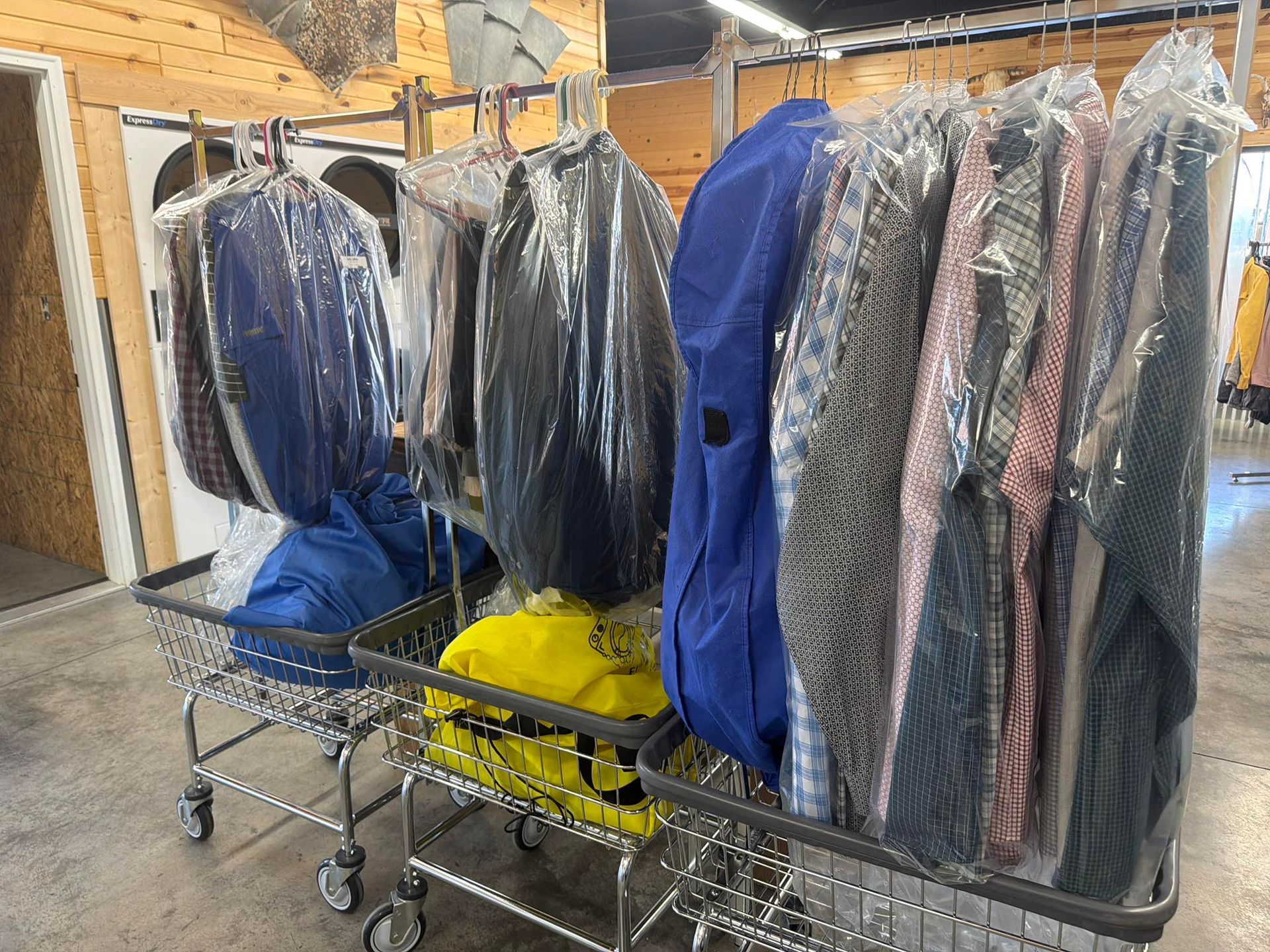Racks of plastic-covered suits and garments in a store or dry-cleaning area