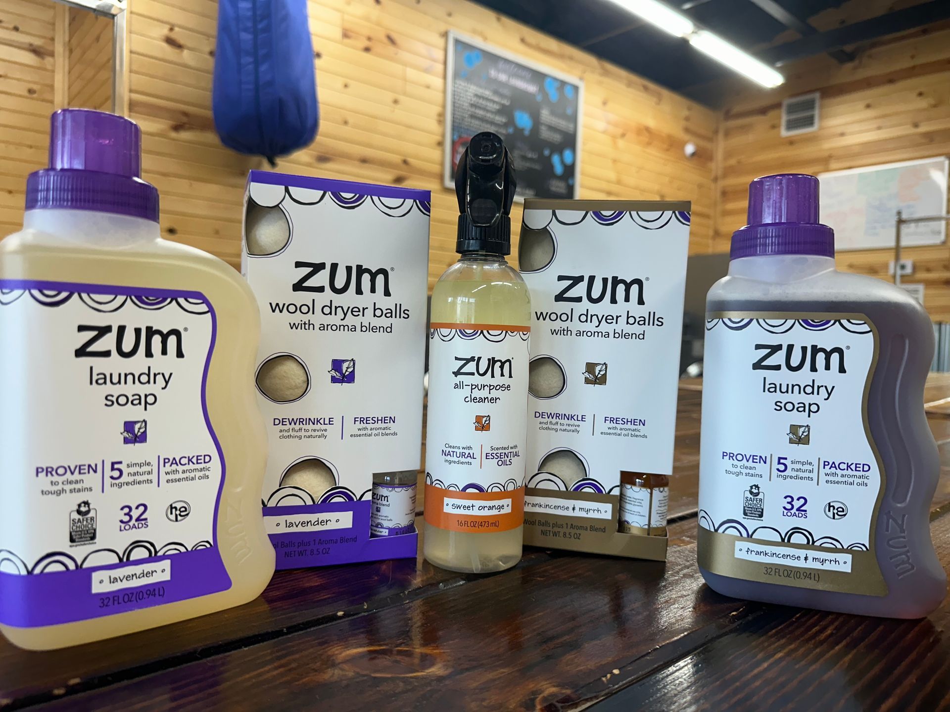 Assorted Zum laundry and body care products on a wooden shelf in a rustic room
