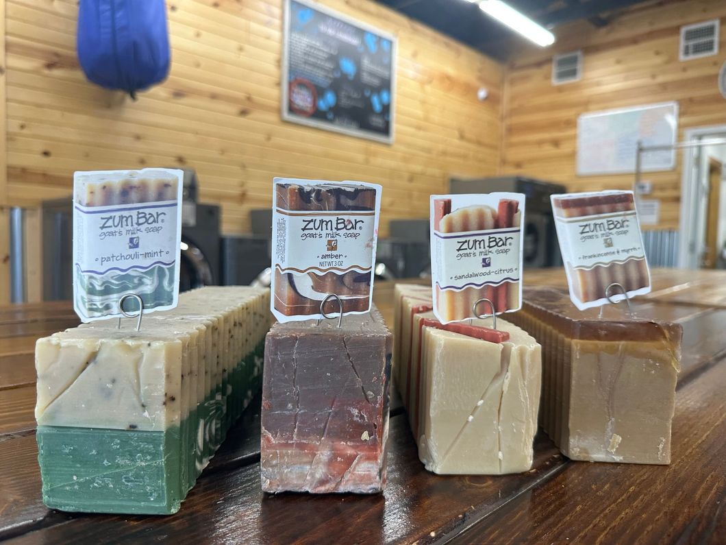 Assorted handmade soaps with labels on a wooden counter inside a rustic shop