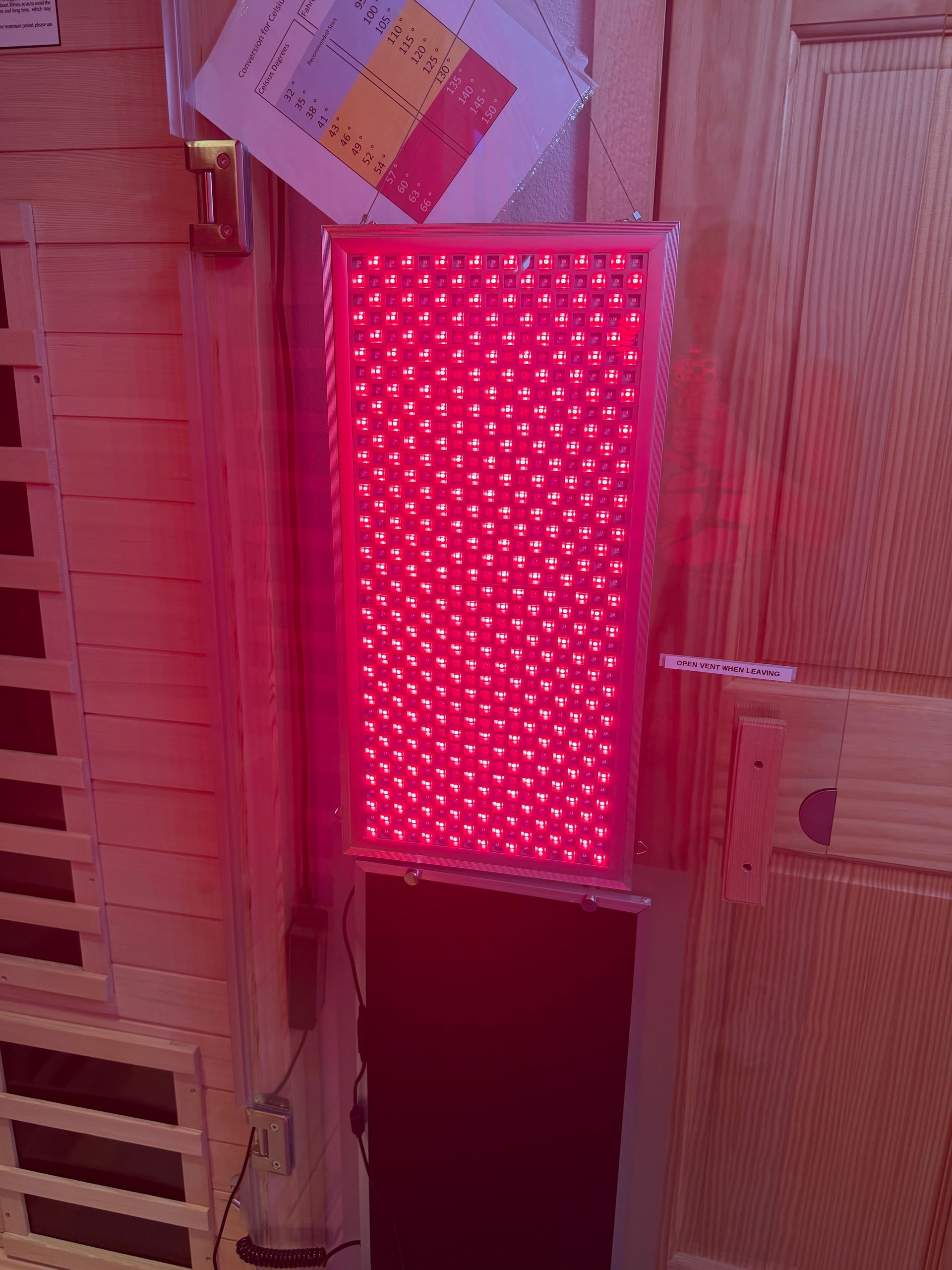 Bright red illuminated LED panel mounted on a wooden wall indoors