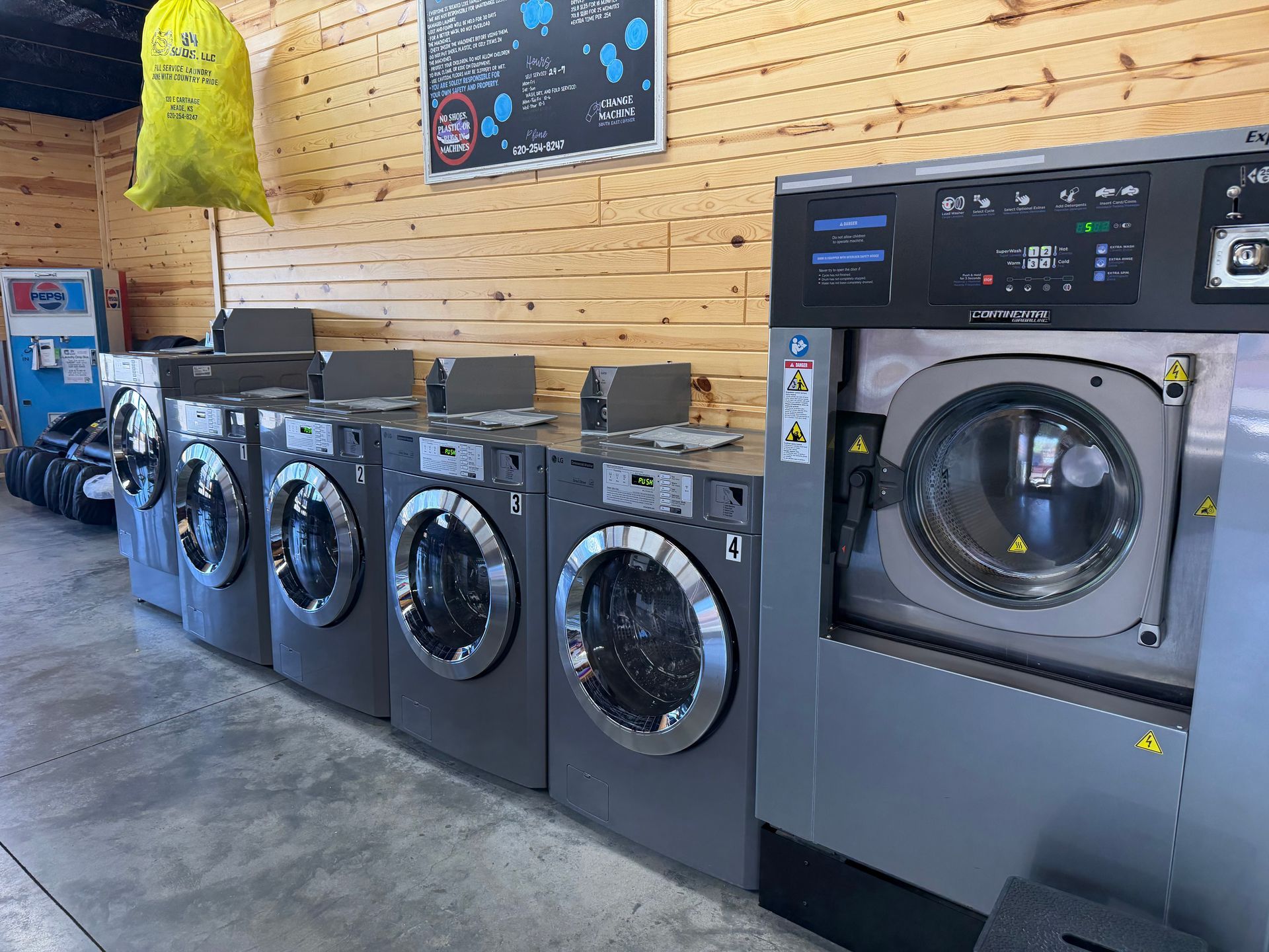 People using laundromat washers and dryers, with one woman folding laundry in front and another seated nearby