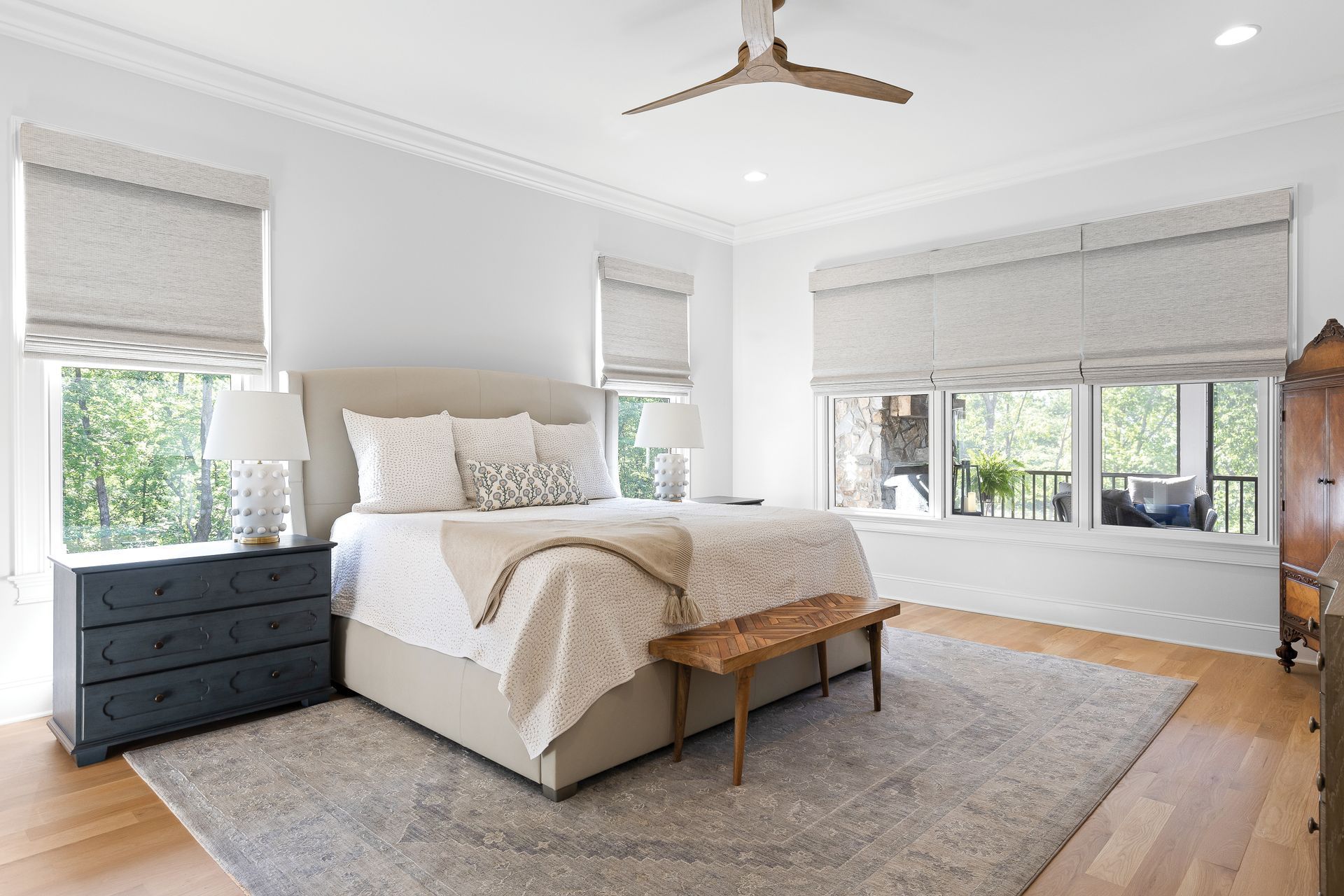 A bedroom with a bed , dresser , nightstand , rug and ceiling fan.