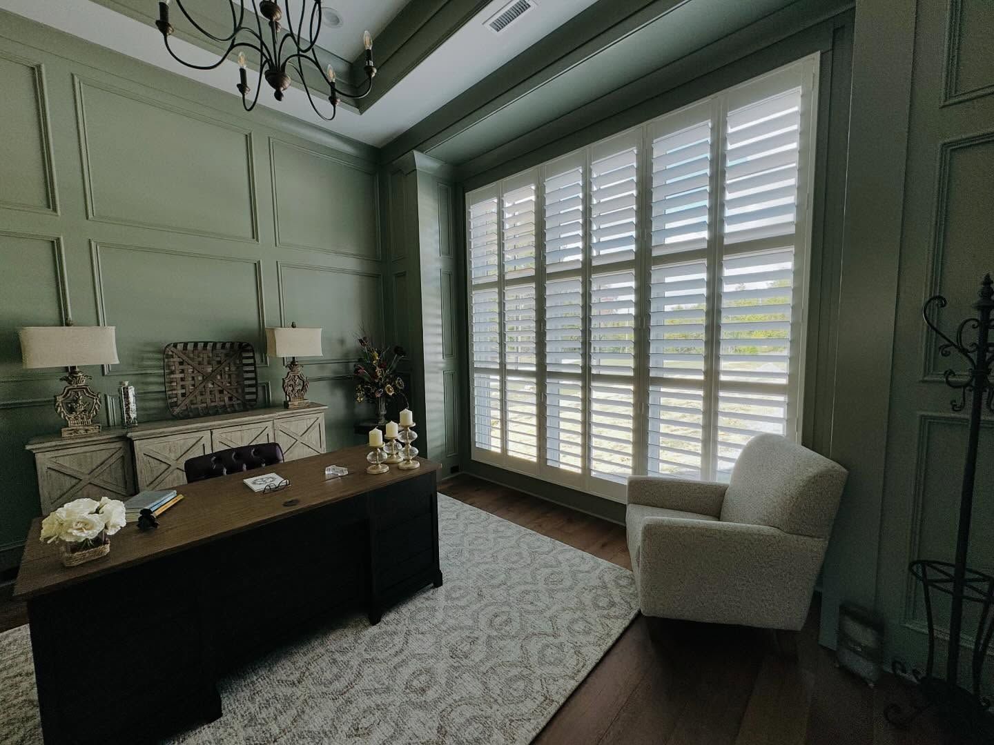 Elegant green home office with a desk, armchair, and large window with shutters