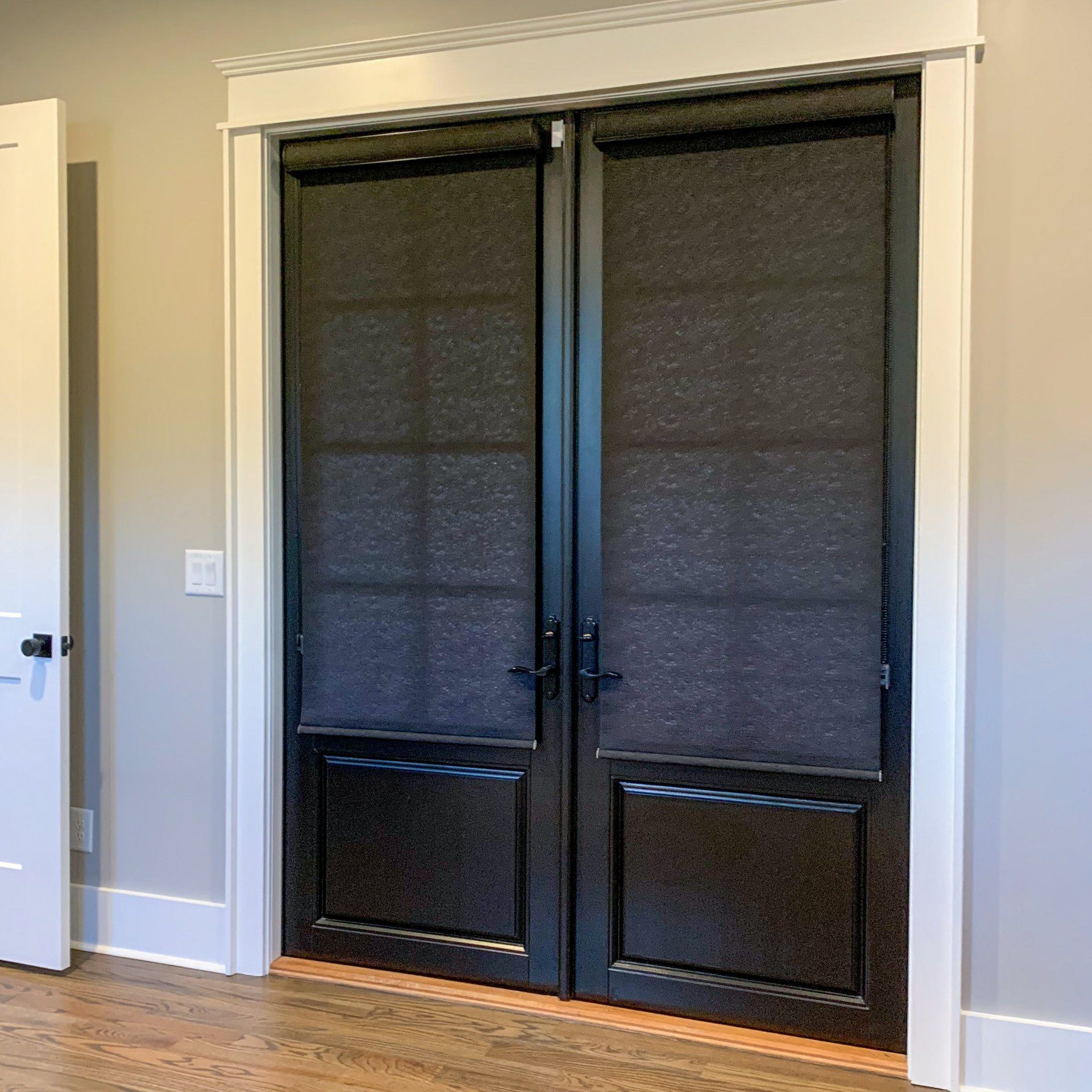 A pair of black doors with blinds on them in a room.