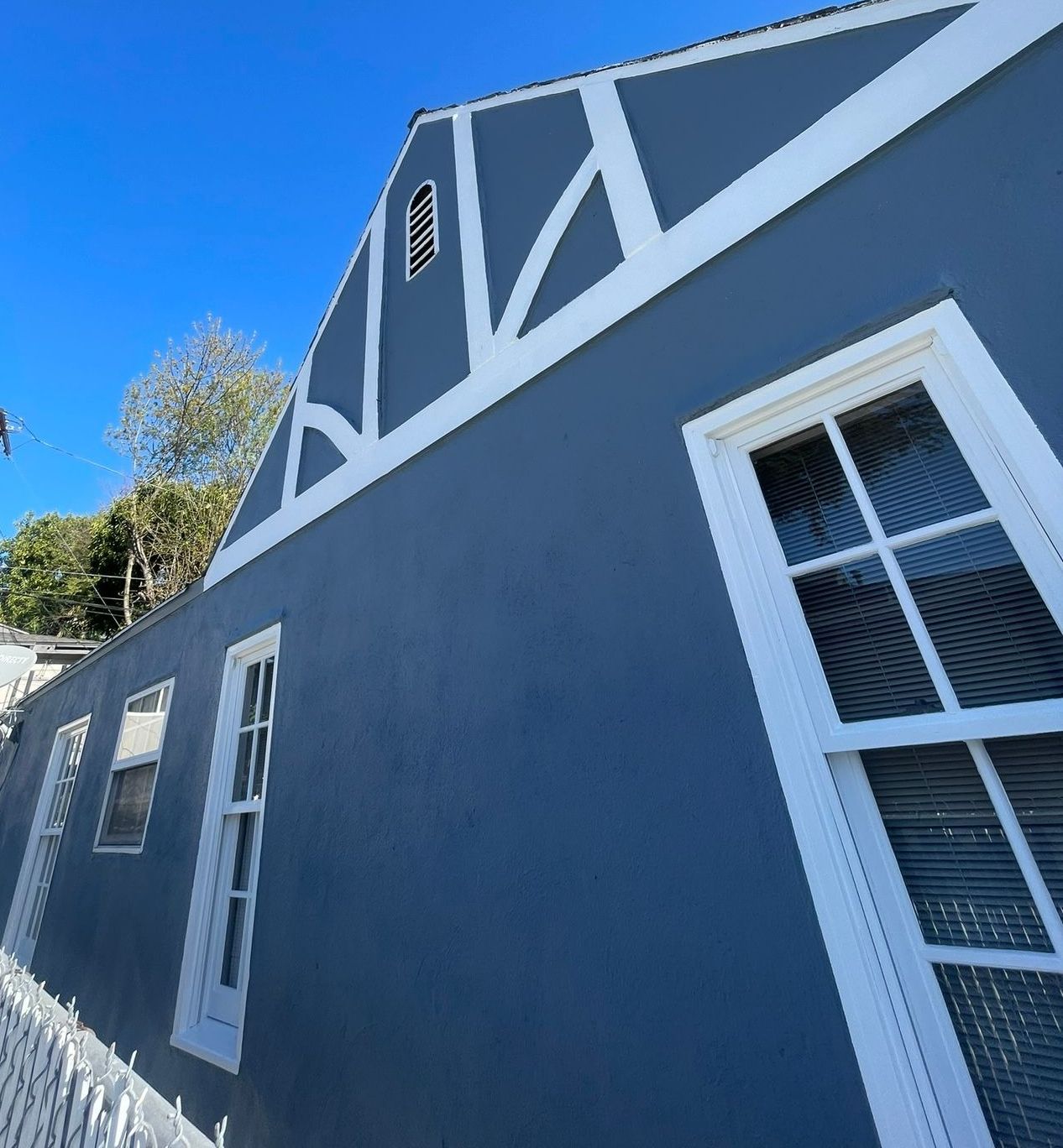 A man on a ladder paints the side of a house