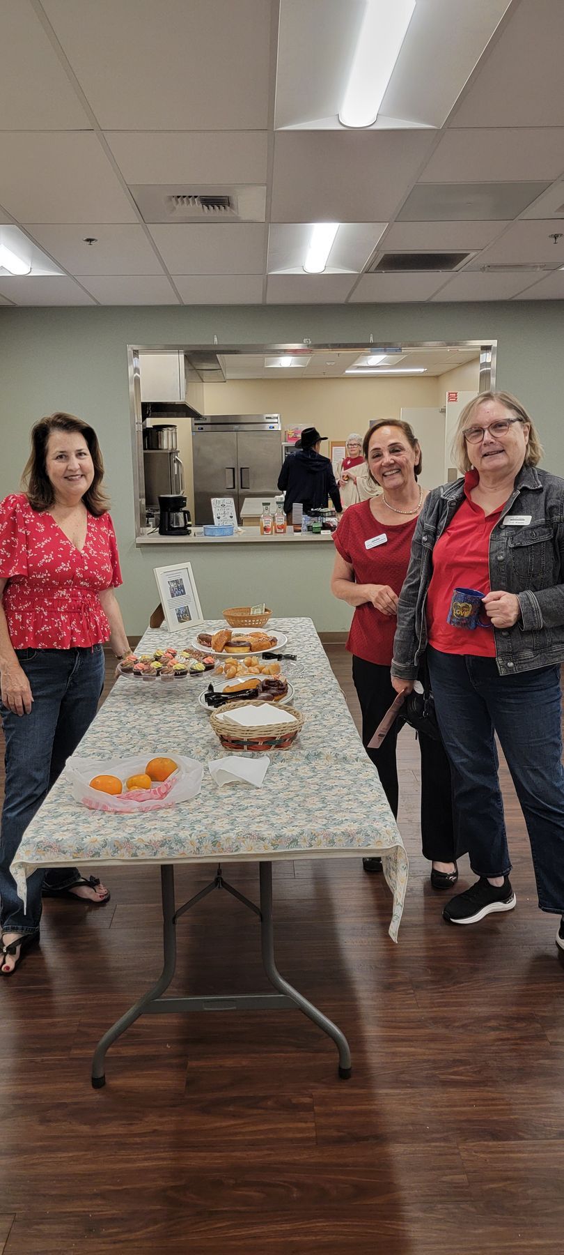 Four people standing behind a buffet table with desserts in a meeting room Four people standing behind a buffet table with desserts in a meeting room