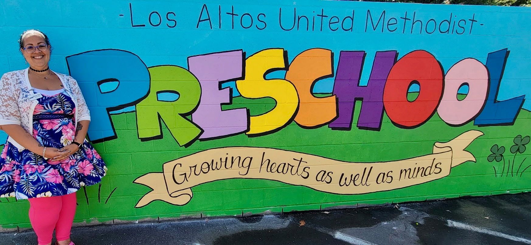 Colorful preschool mural with large “PRESCHOOL” text and the director standing on the left