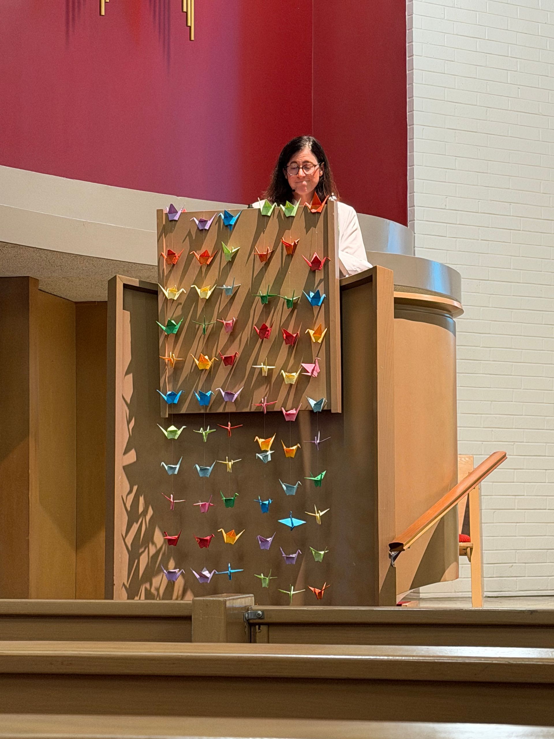 Pastor speaking at a church pulpit decorated with colorful paper butterflies