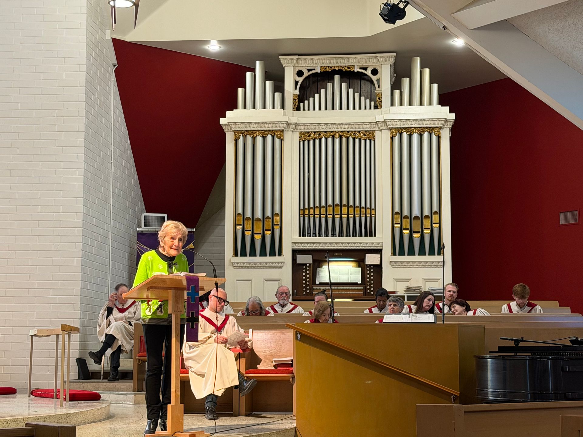 Person speaking at a podium in front of a large pipe organ inside a church sanctuary