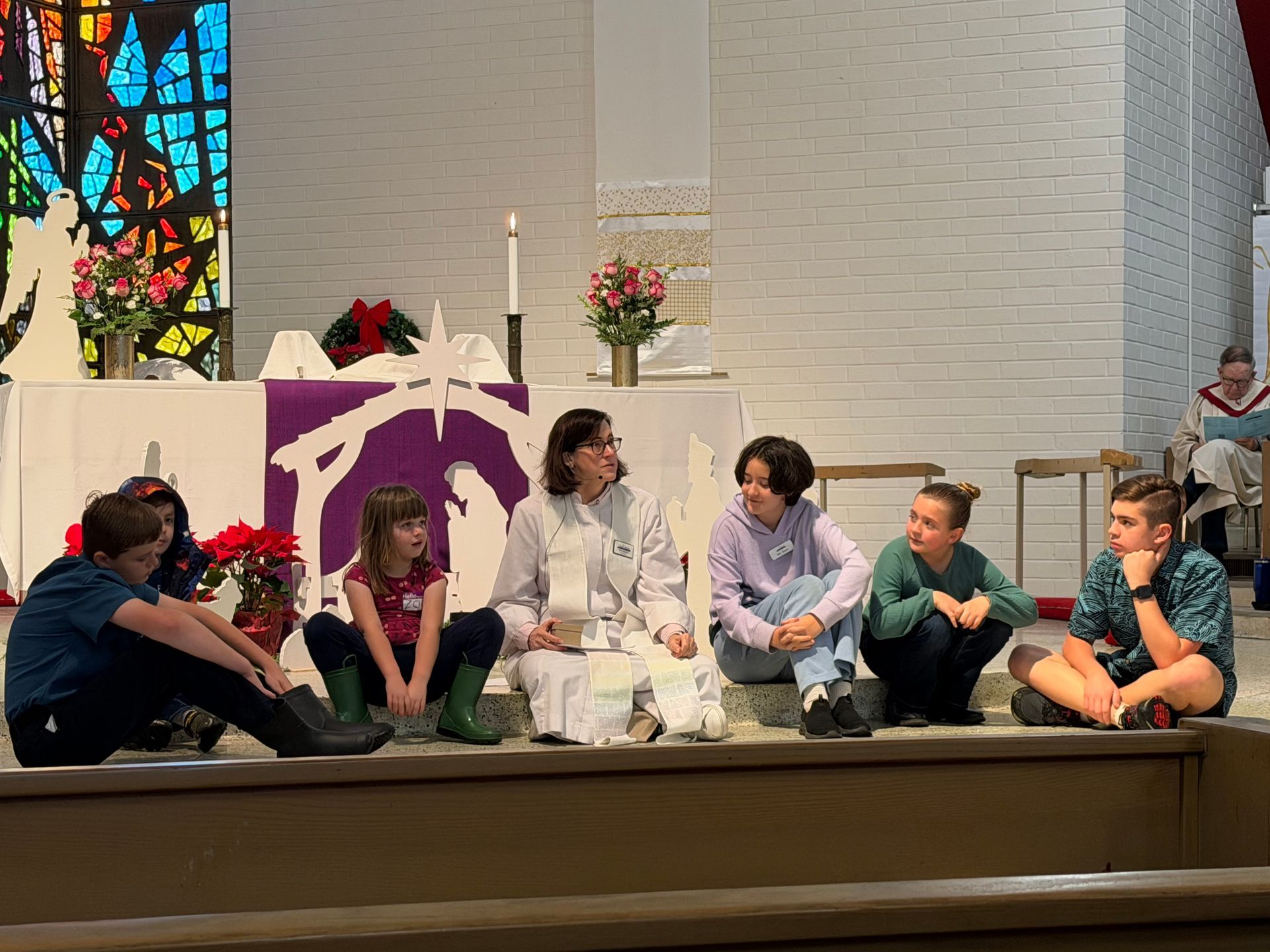 Children sitting on a church alter with a purple-and-white display and stained glass background Children sitting on a church alter with a purple-and-white display and stained glass background