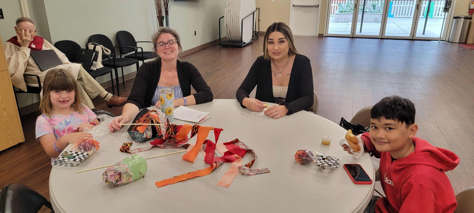People around a table sharing snacks and crafts in a bright room People around a table sharing snacks and crafts in a bright room
