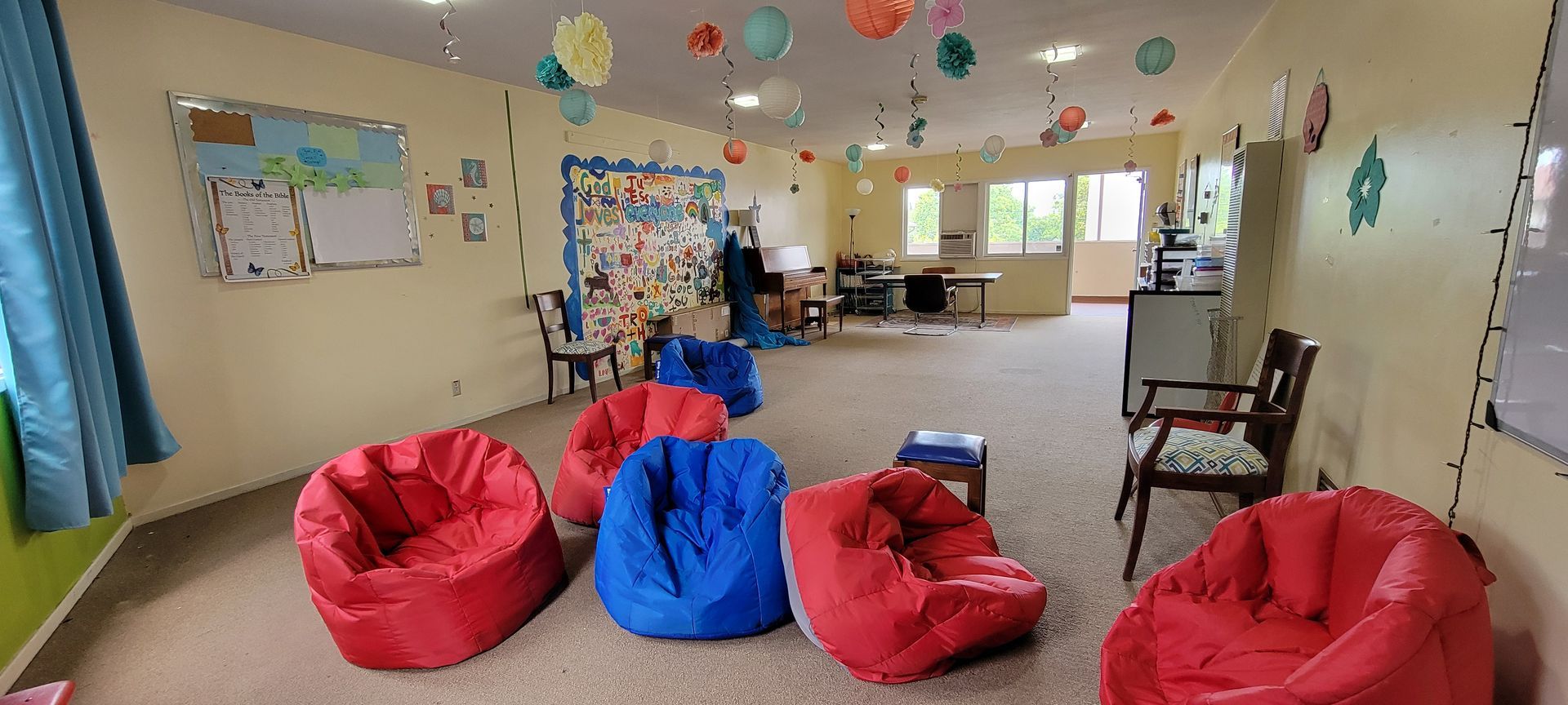 Bright classroom with colorful beanbag chairs, tables, wall art, and daylight from windows Bright classroom with colorful beanbag chairs, tables, wall art, and daylight from windows