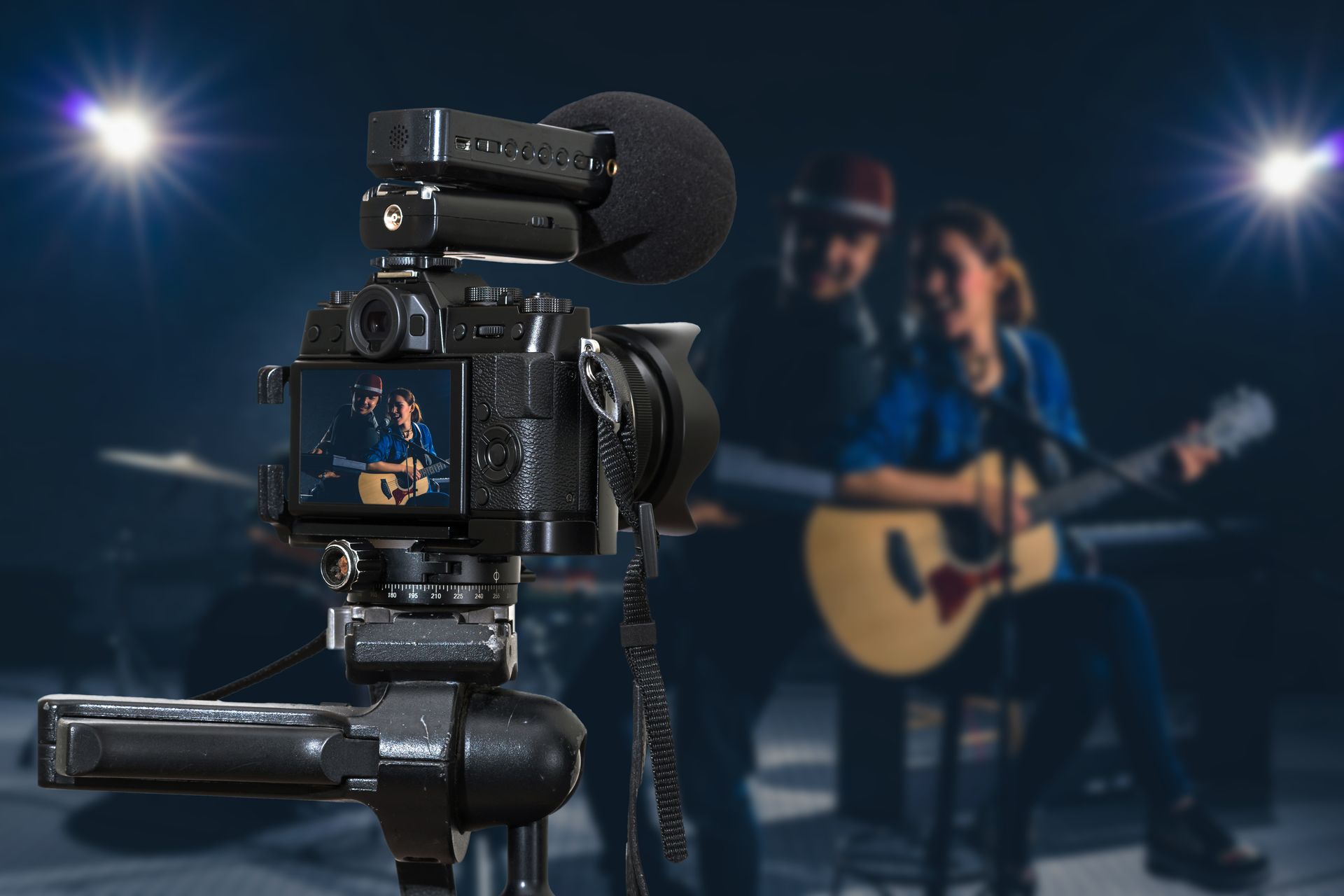 Camera filming a guitarist with bandmate.