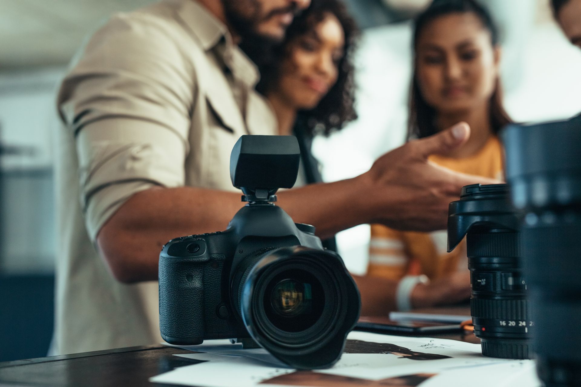 Camera on table with three people looking at it, discussing.