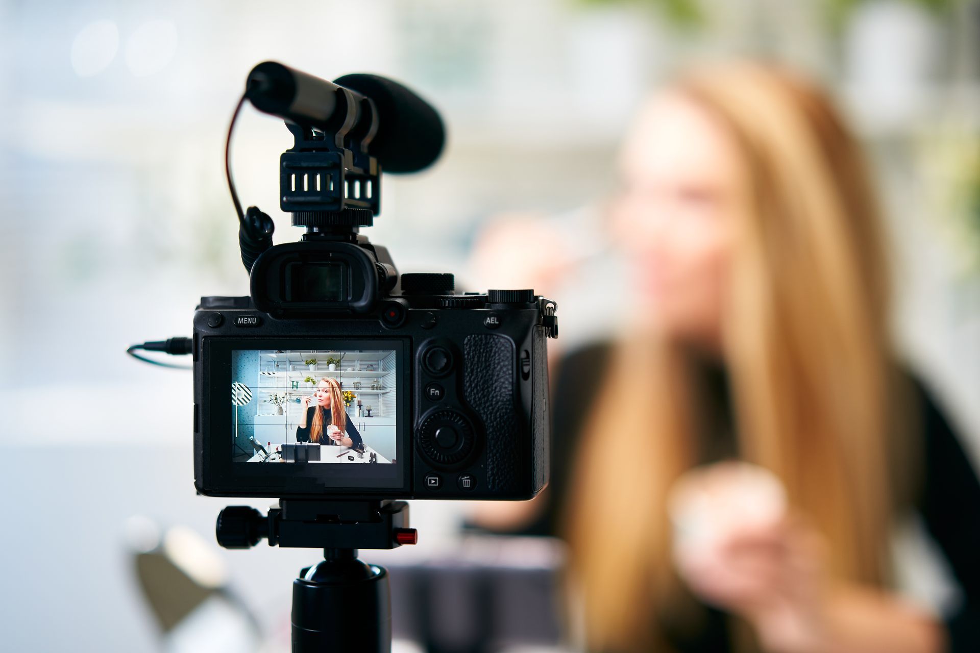 Camera filming a blonde woman indoors.