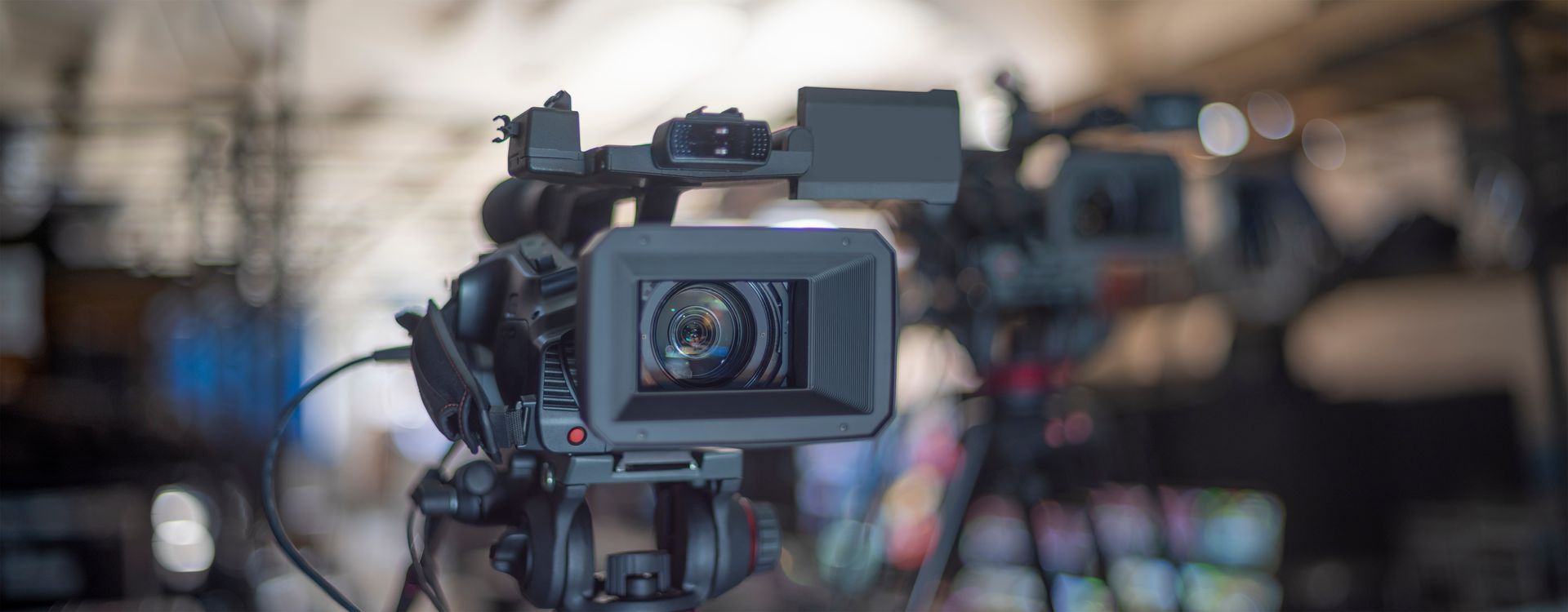A close-up of a professional video camera on a tripod.