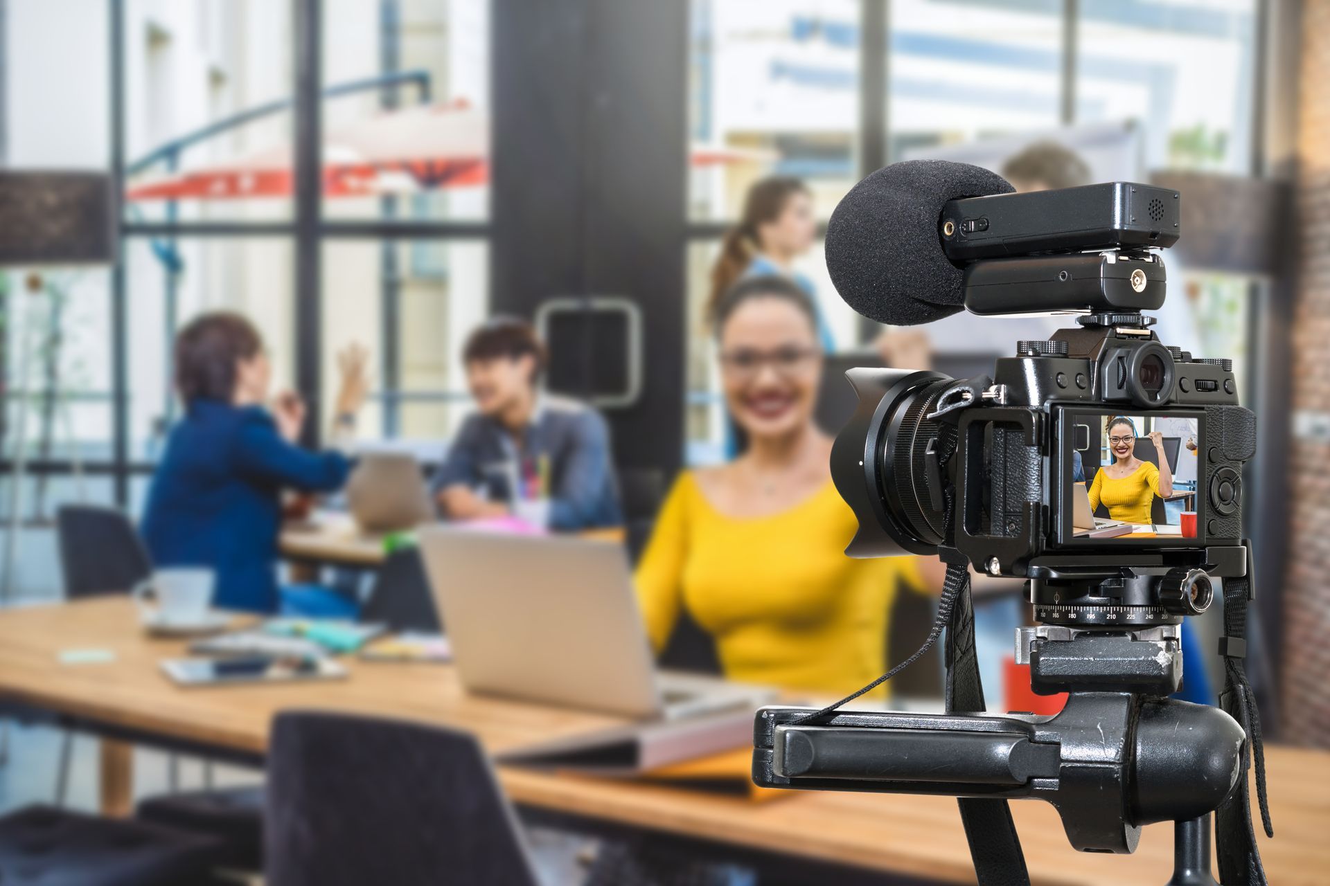 Camera on tripod filming a woman in yellow shirt.