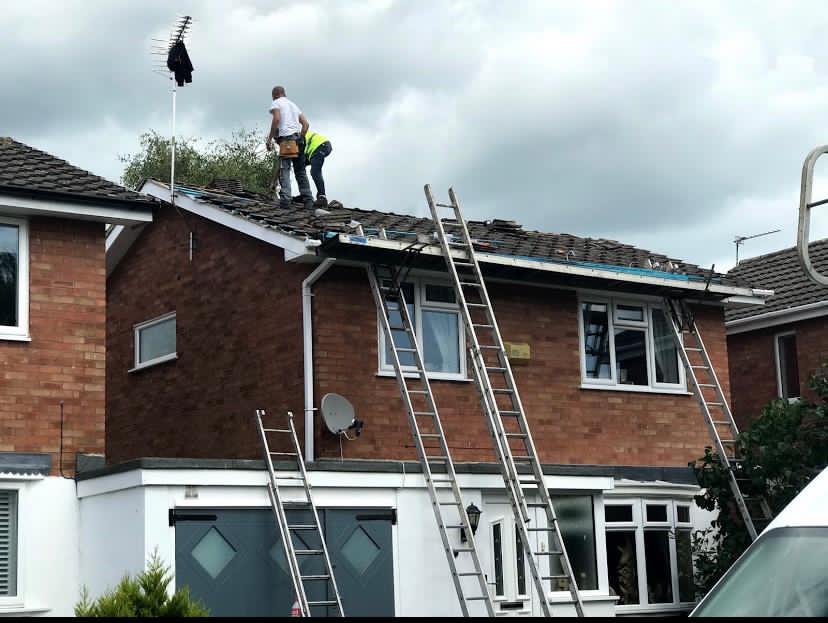 two workers standing atop a roof