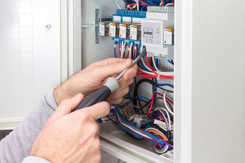 A Man Is Working on An Electrical Box with A Screwdriver — All Star Electrical Services in Horsley, NSW