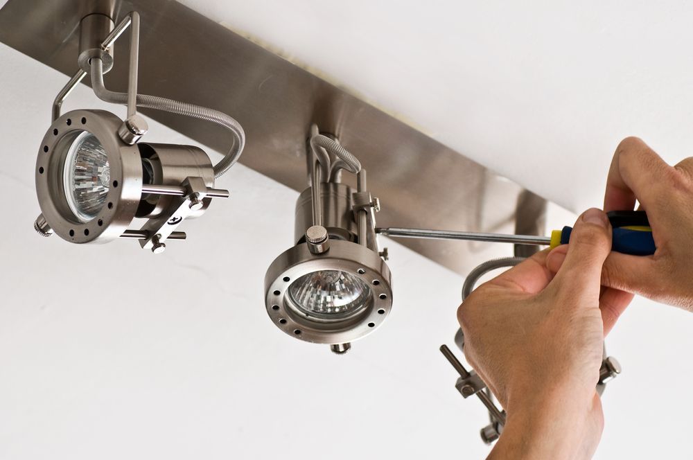 A Person Is Fixing a Light with A Screwdriver — All Star Electrical Services in Horsley, NSW