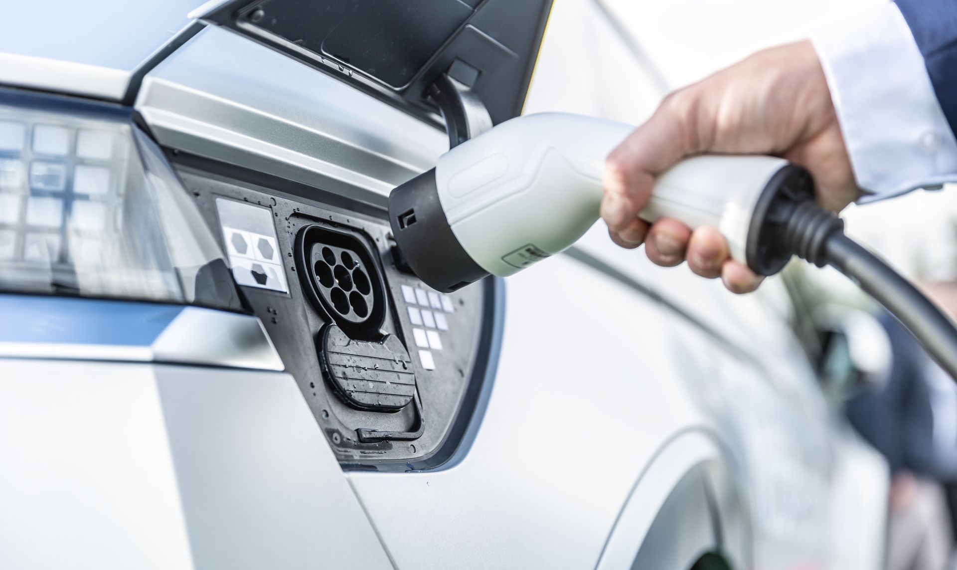 A Person Is Charging an Electric Car with A Charger — All Star Electrical Services in Horsley, NSW