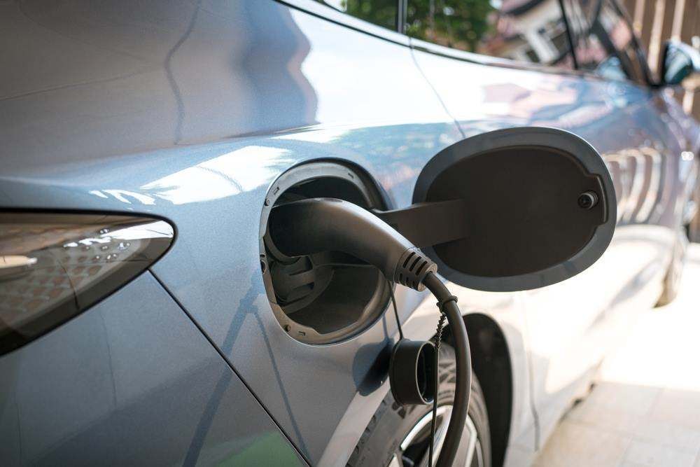 Electric Car Charging Cable Plugged Into A Light Blue Car — All Star Electrical Services in Wollongong, NSW