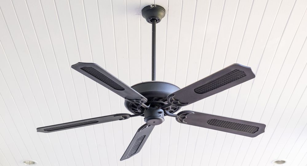 A Black Ceiling Fan Is Hanging From The Ceiling Of A Room — All Star Electrical Services in Thirroul, NSW