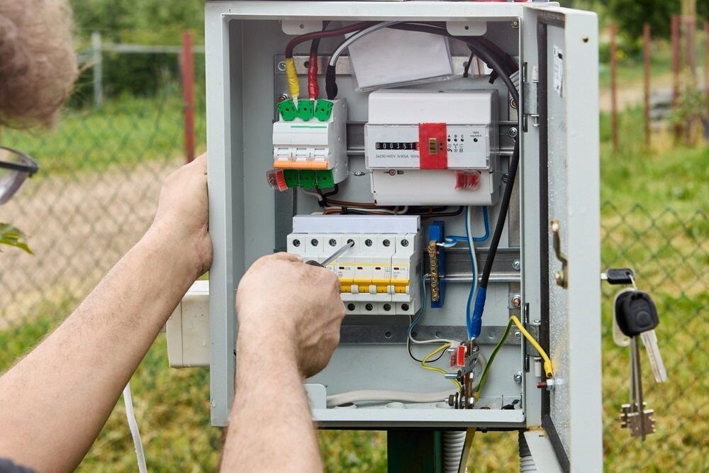 A Man Is Working On An Electrical Box With A Screwdriver — All Star Electrical Services in Unanderra, NSW