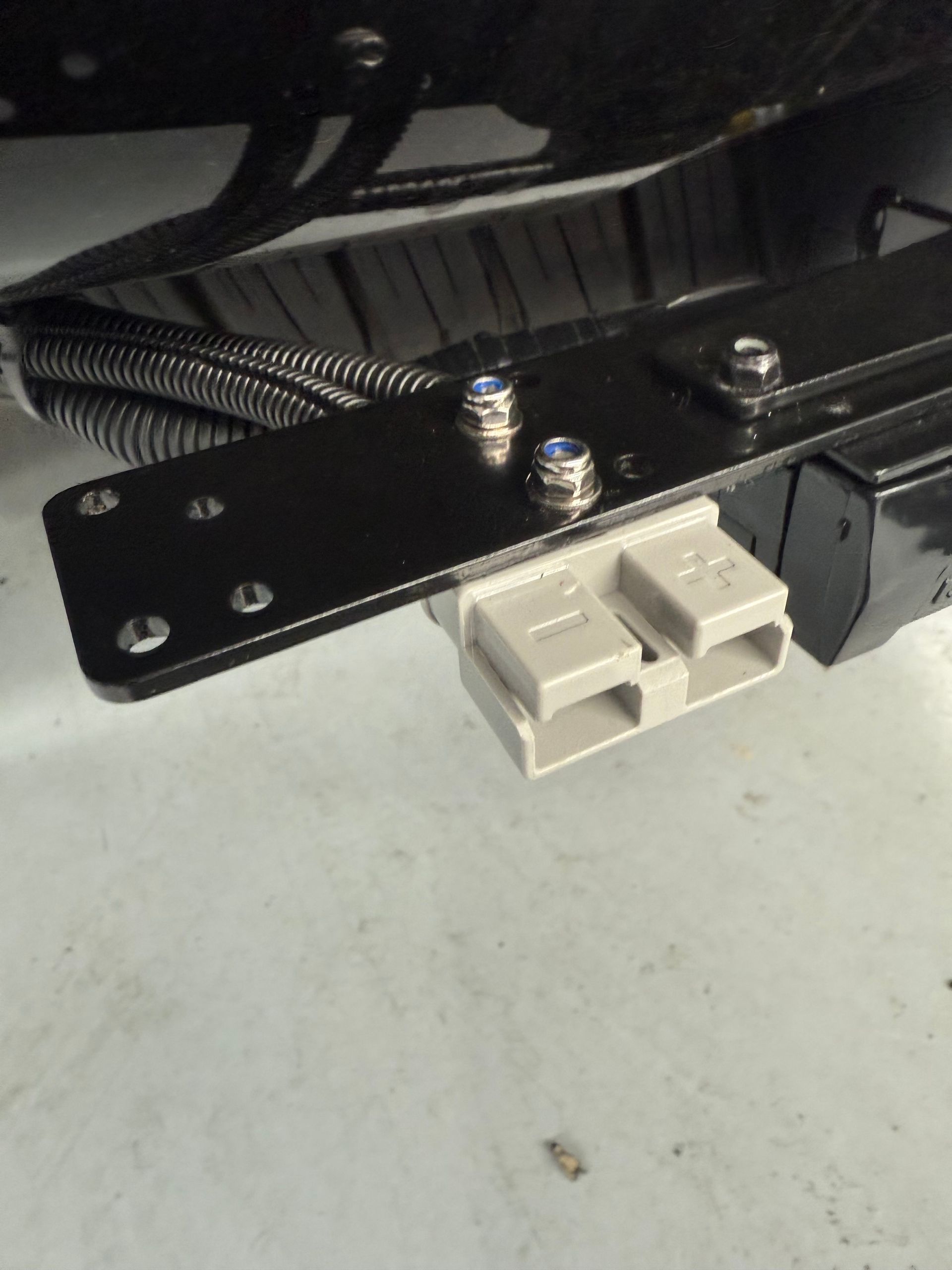 Black metal bracket with a grey electrical connector, held together with silver bolts.