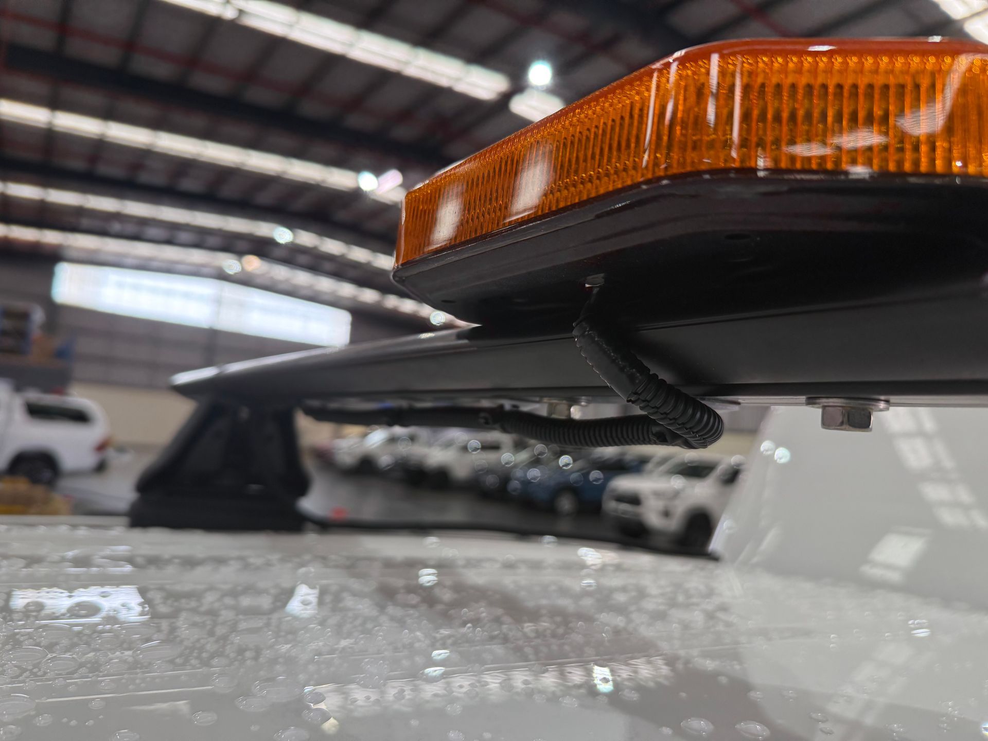 Close-up of an amber emergency light bar mounted on a white vehicle roof. Black wires are visible.