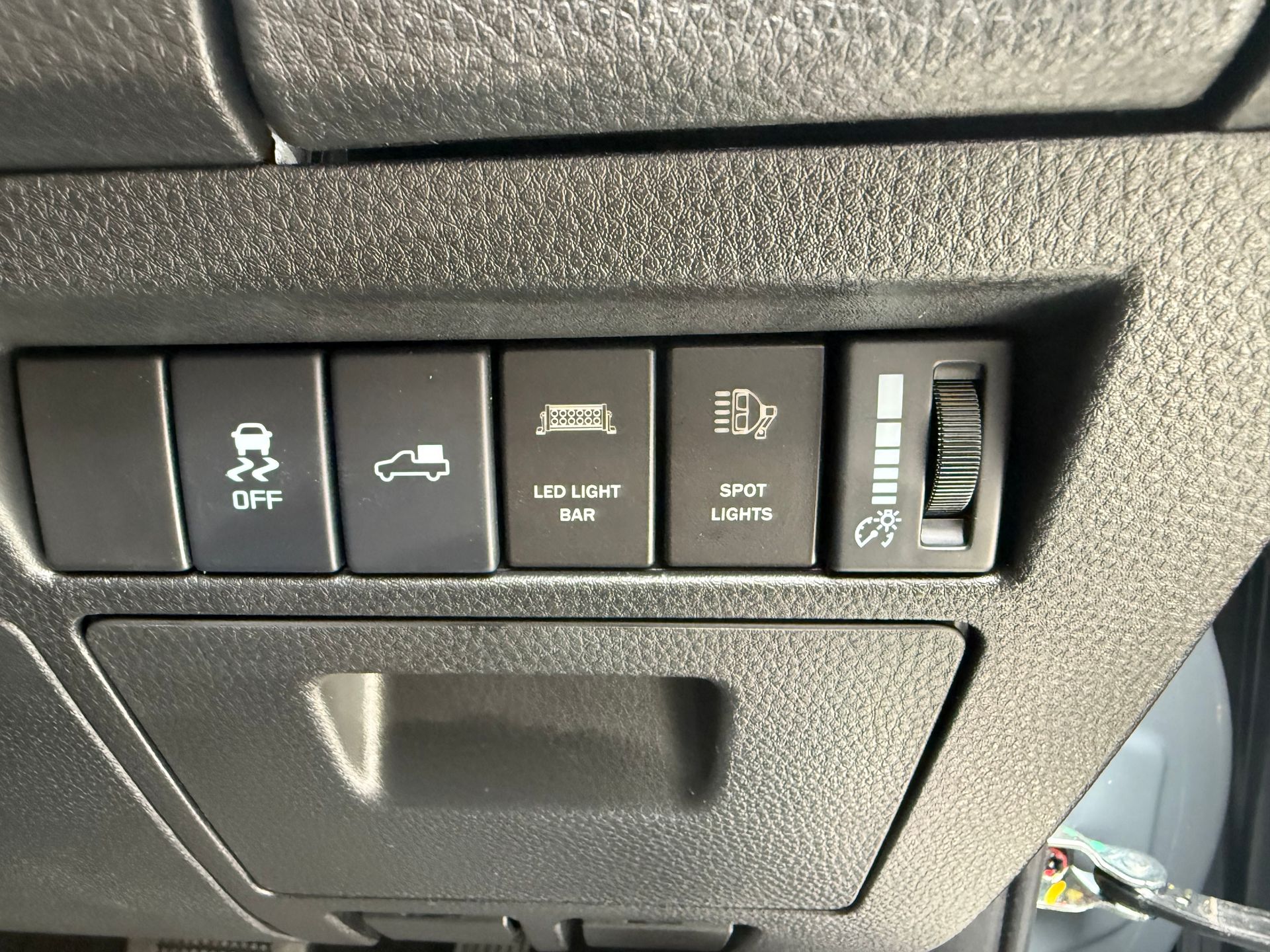 Dashboard control panel with buttons for off-road features, including sway bar, bed access, lights, and switch for unknown function.