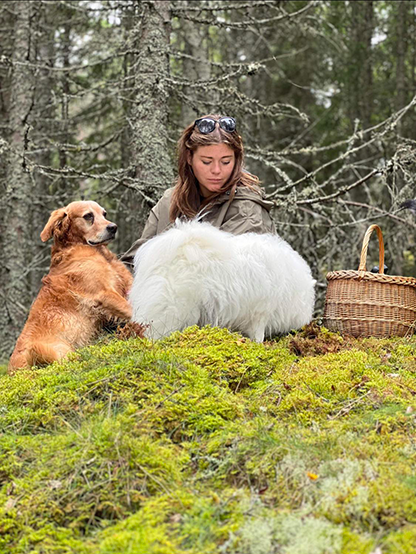 Felicia sitter i skogen med några hundar