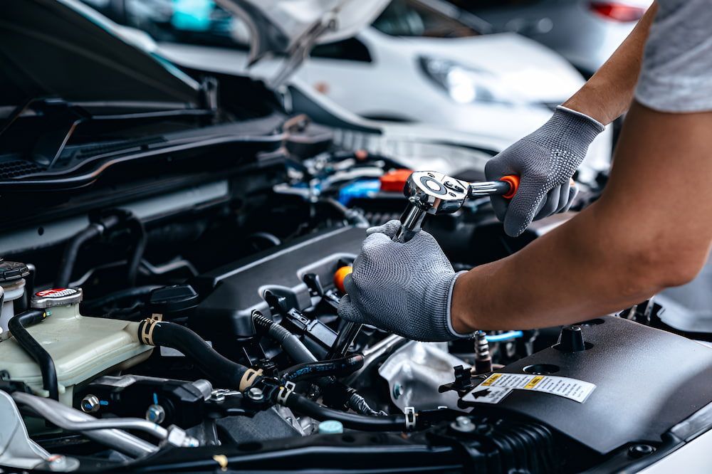 A Man Is Working On The Engine Of A Car With A Wrench — Josh's Diesel Services in Boyne Island, QLD