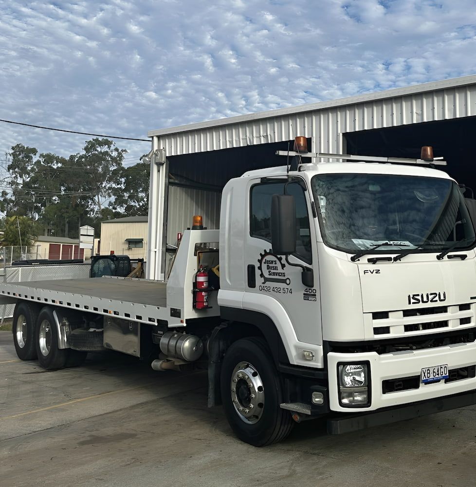 A White Isuzu Tow Truck Is Parked In Front Of A Garage — Josh's Diesel Services in Boyne Island, QLD