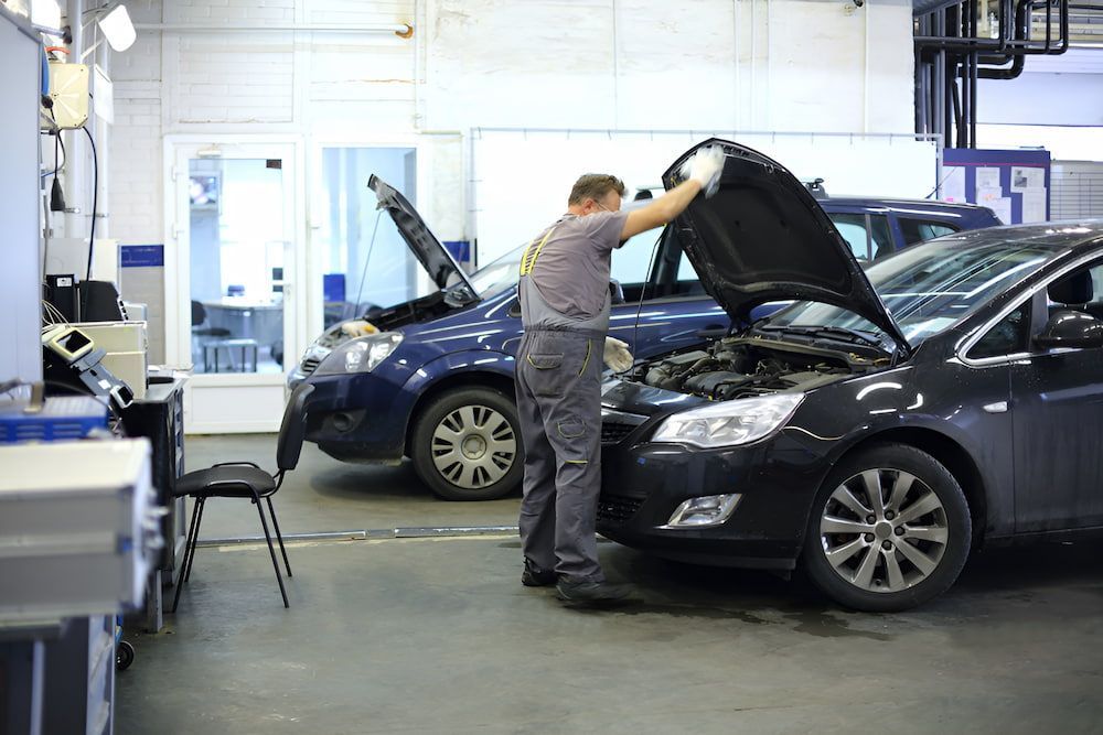 A Man Is Working On A Car In A Garage With The Hood Open — Josh's Diesel Services in Gladstone, QLD