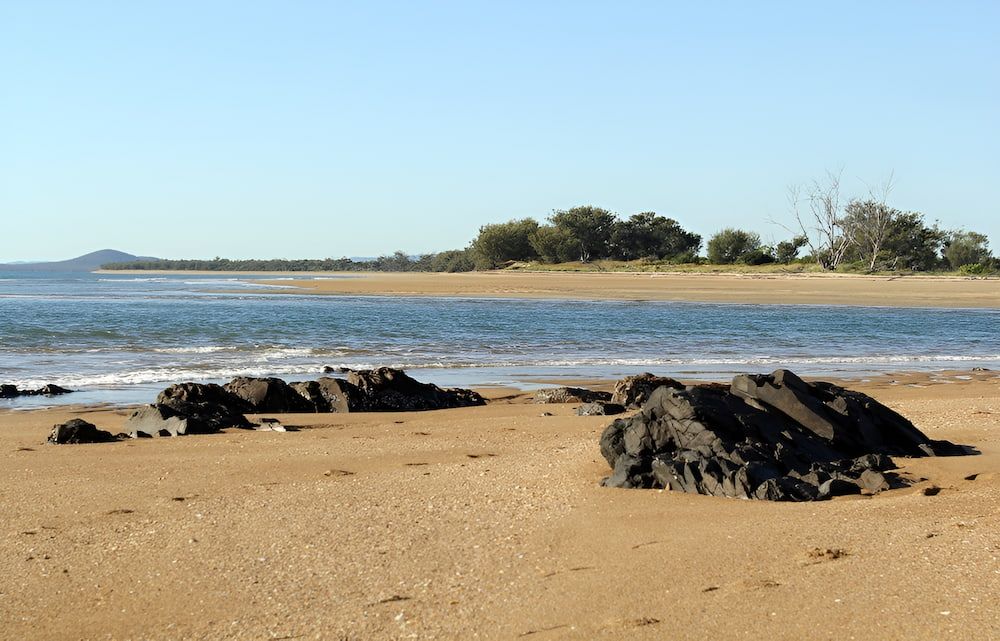 A Beach With Rocks And A Body Of Water — Josh's Diesel Services in Tannum Sands, QLD