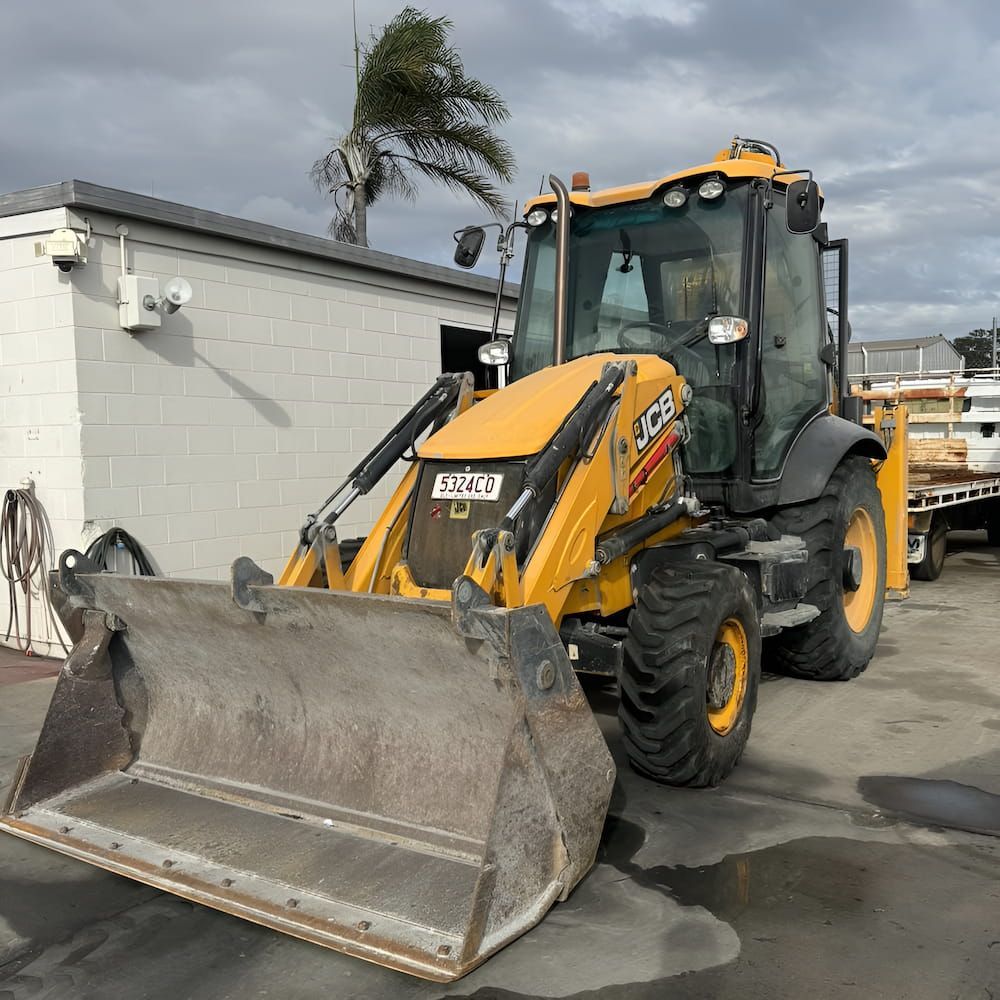 A Yellow Tractor With A Large Bucket Is Parked In Front Of A Building — Josh's Diesel Services in Tannum Sands, QLD