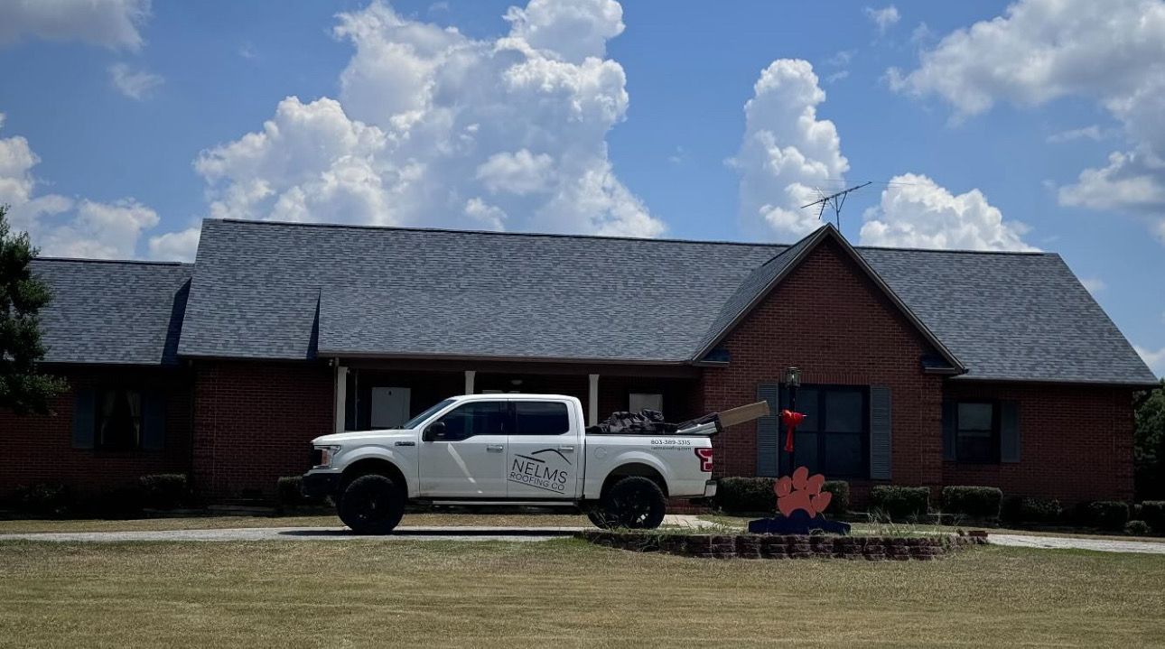 White pickup truck parked in front of a rustic brick building under a blue sky with clouds