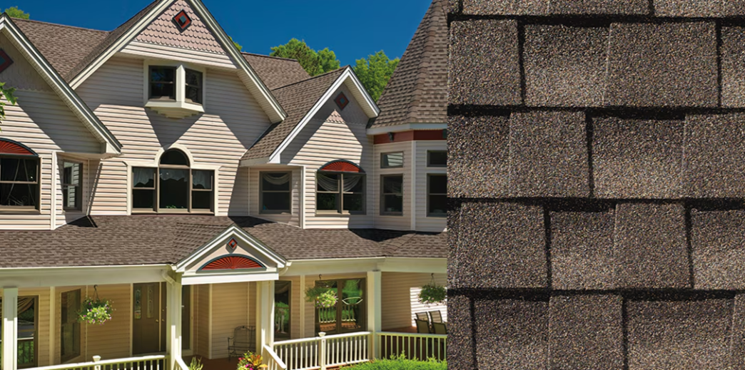 Suburban house exterior with beige siding, gray shingled roofs, and a large stone chimney in the foreground