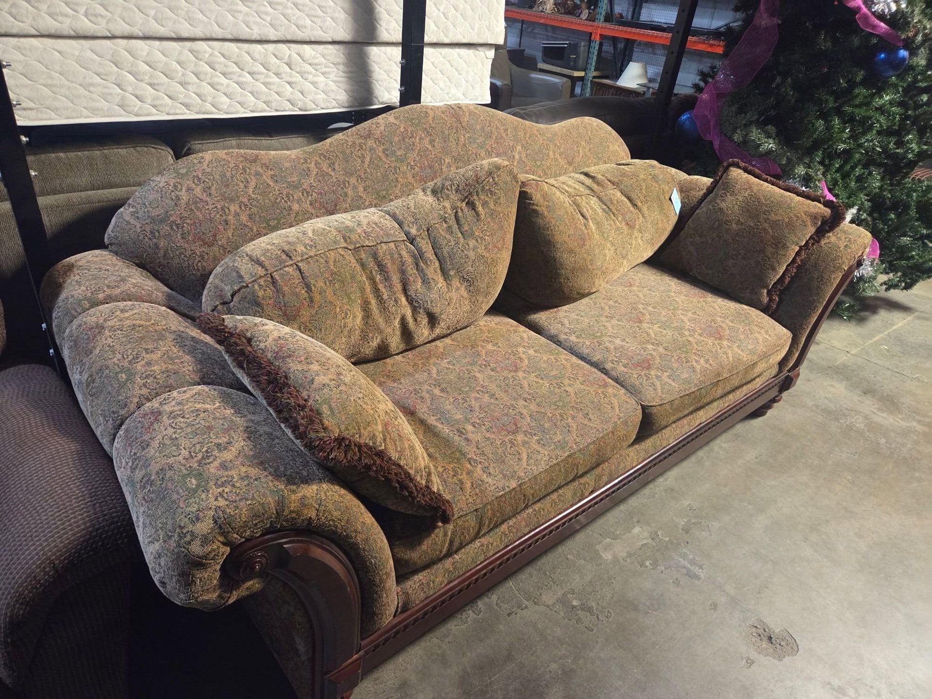 Brown patterned couch with matching pillows on a concrete floor in a warehouse-like room