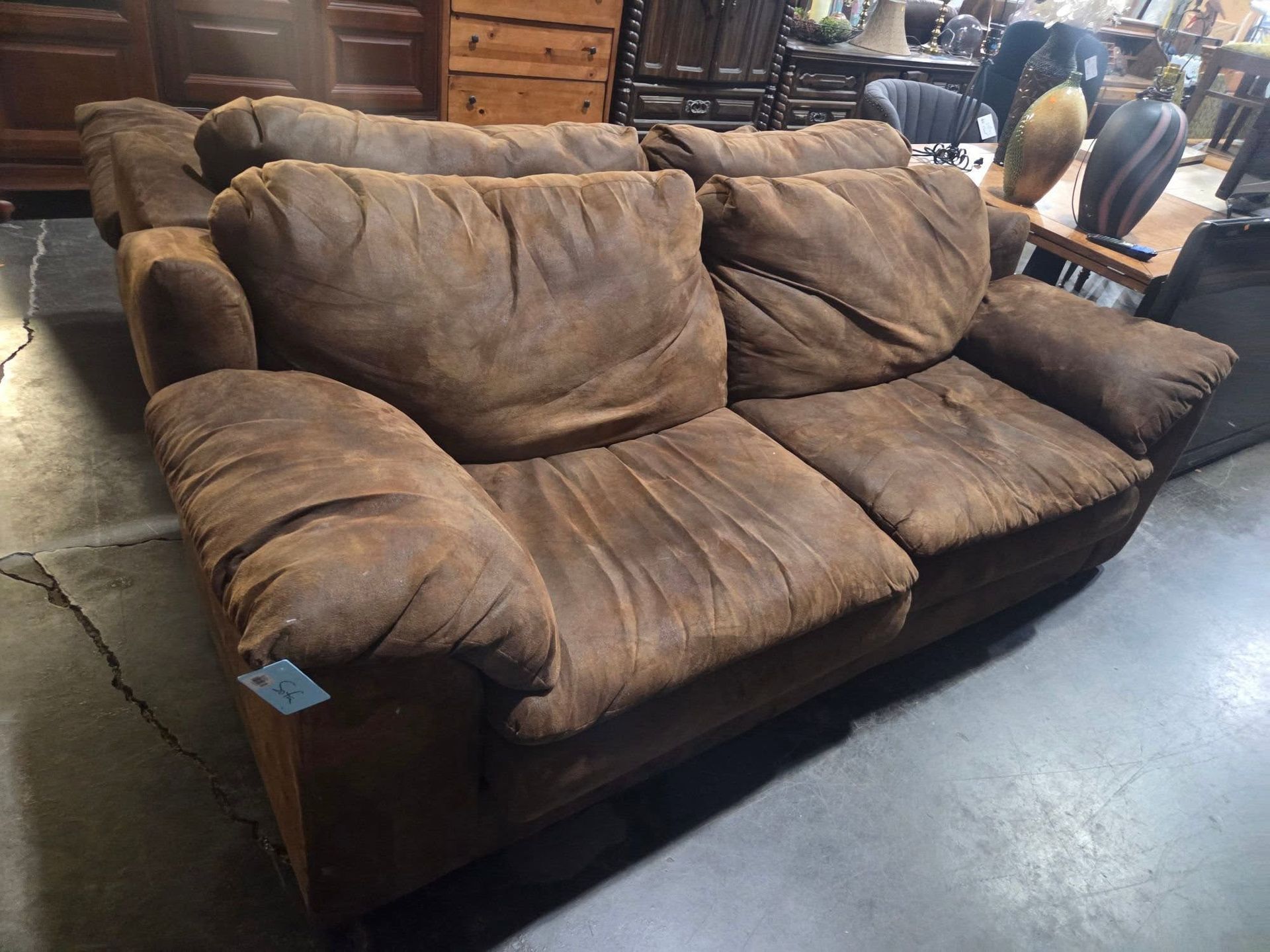 Brown upholstered sofa with two large cushions in a store or warehouse setting