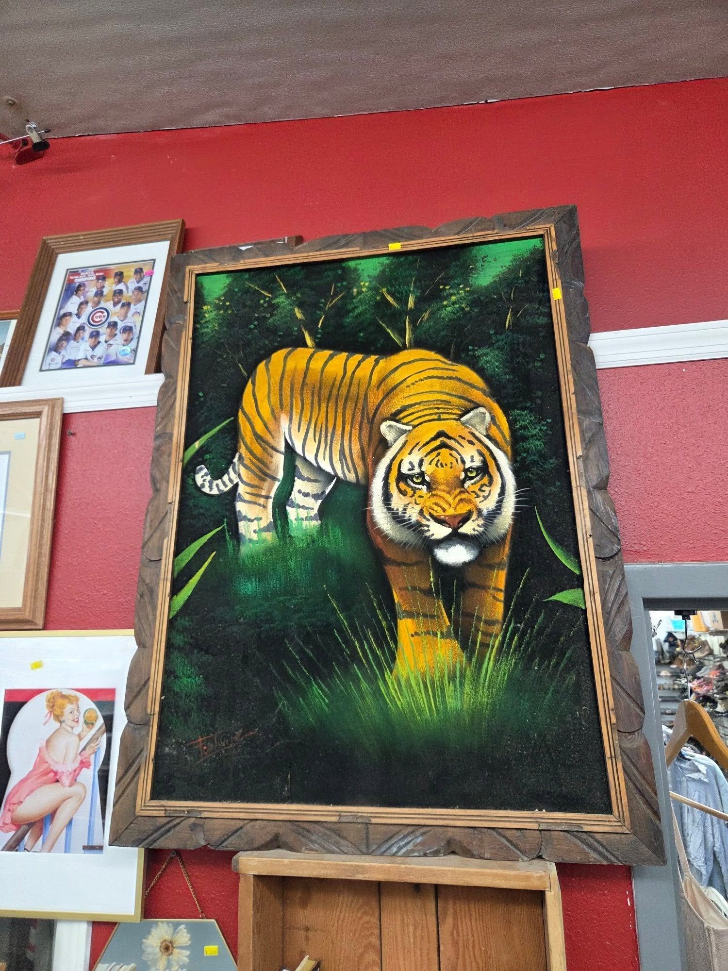 Framed painting of a tiger walking through a dark green jungle on a red wall