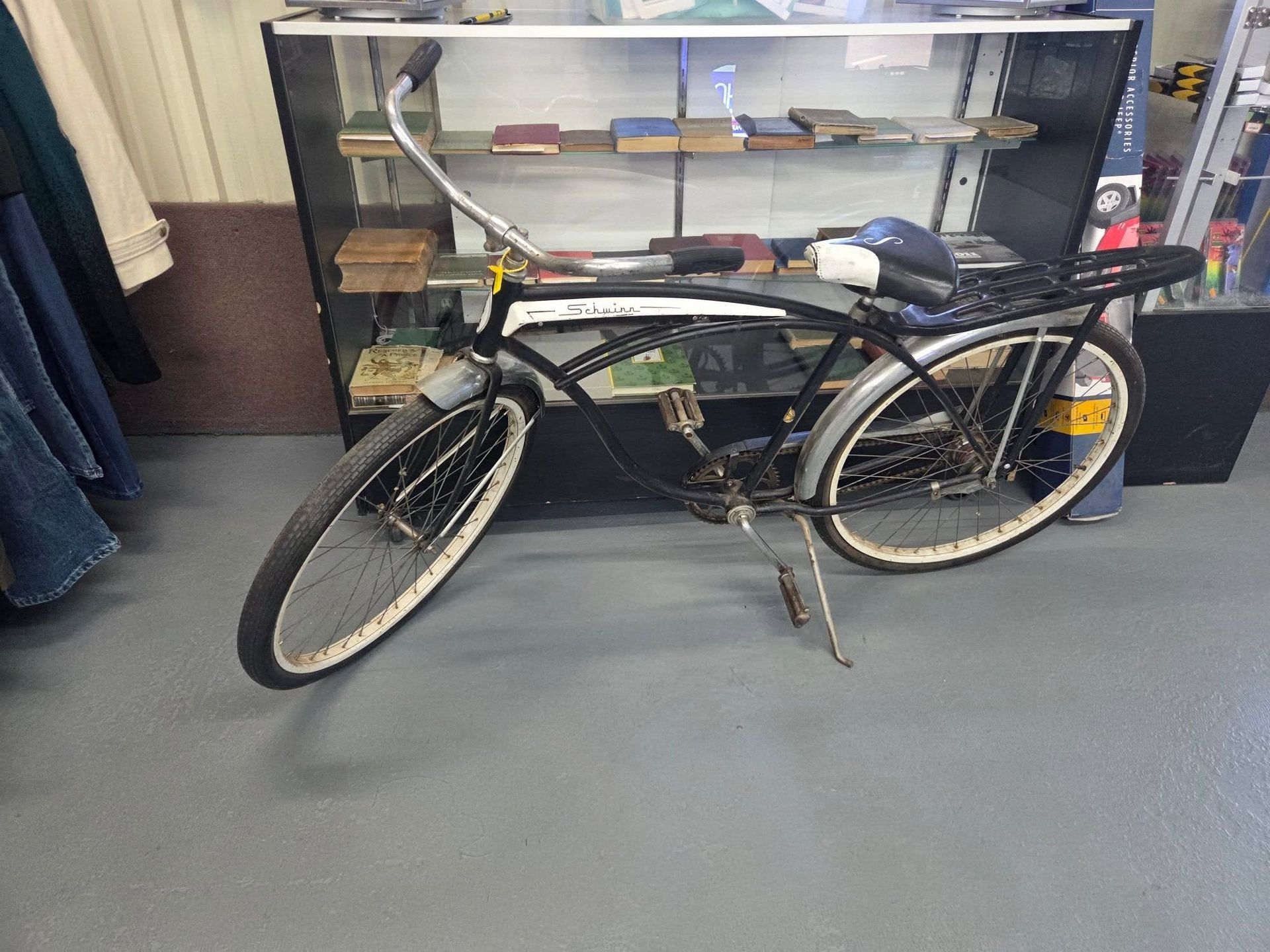 Black bicycle leaning in front of a glass display cabinet in an indoor room
